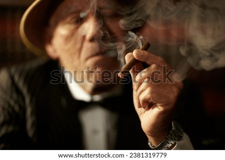 Old man, smoking and cigarette in hand with smoke and crime boss of mob with a decision. Gangster, face and senior person with vintage cigar in mafia or country club with luxury, vice or habit Royalty-Free Stock Photo #2381319779