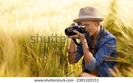 Woman, camera and photography in grass with travel, vacation and holiday with wheat field and plants. Nature, photographer and outdoor with blog and countryside with photo for adventure and journey