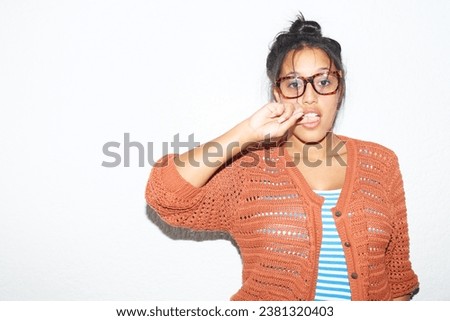 Studio background, portrait and a flirty woman biting finger for fashion, streetwear or urban culture. Model, glasses and a young girl or person with mockup, flirting or stylish on a backdrop