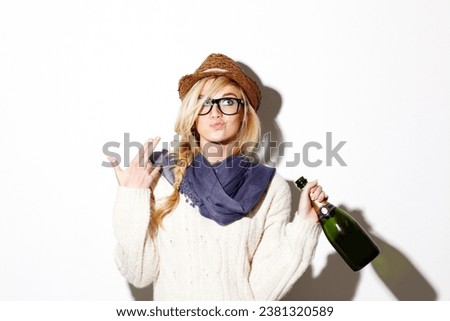 Woman, blonde and hat with champagne of nerd, geek or hipster thinking against a studio background. Attractive female person with glasses, nerdy or fashion style gesture and holding bottle of alcohol