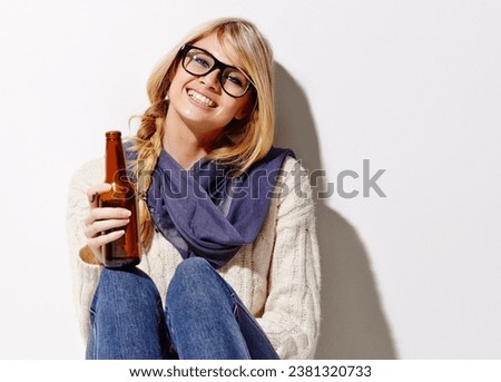 Happy woman, portrait and relax with beer of nerd, geek or hipster against a studio background. Attractive female person or model smile with glasses, nerdy or fashion style holding bottle of alcohol