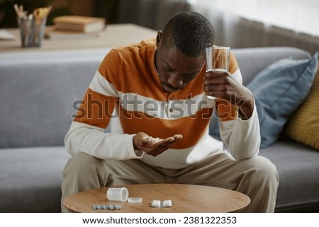 Portrait of depressed African American man holding handful of pills in hand while suffering from mental health issues Royalty-Free Stock Photo #2381322353