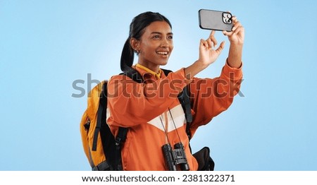 Hiking studio, phone photo and woman trekking, backpacking and take picture of landmark, sightseeing or holiday. Freedom, vacation camper and smartphone photography for tour memory on blue background
