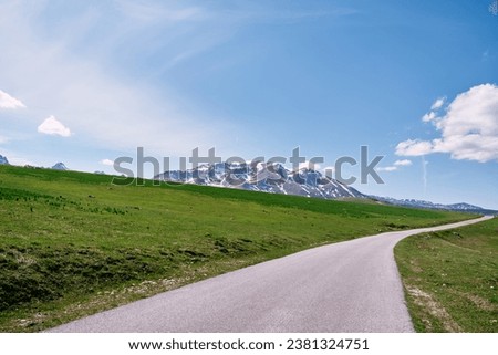 Highway in a green valley overlooking snow-capped mountains