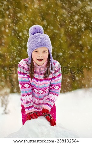 happy kid making a snowman. funny little girl on a walk in the winter outdoors