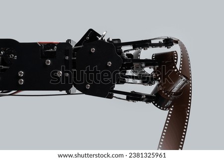 Real robotic hand with film stock. Concept of AI in motion picture and photography industry.