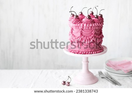 Pink celebration cake with vintage buttercream piped frills and cherries Royalty-Free Stock Photo #2381338743