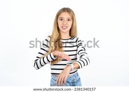 caucasian kid girl wearing striped T-shirt In hurry pointing to watch time, impatience, upset and angry for deadline delay. Royalty-Free Stock Photo #2381340157