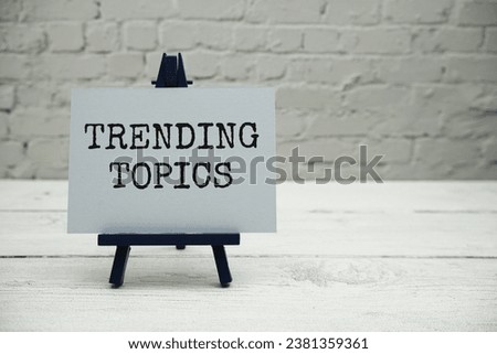 Trending Topics text on white brick wall and wooden background