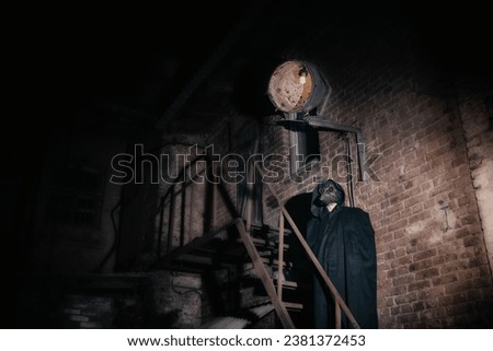 A man in a Venetian plague doctor mask with glowing red eyes against the background of an ancient house