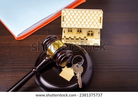 Concept of real estate auction, legal system and division of property after divorce. Gavel and house key on a wooden background. Royalty-Free Stock Photo #2381375737
