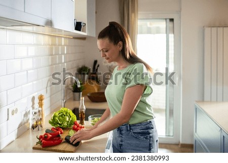 Young woman preparing fresh vegetables in the kitchen Royalty-Free Stock Photo #2381380993