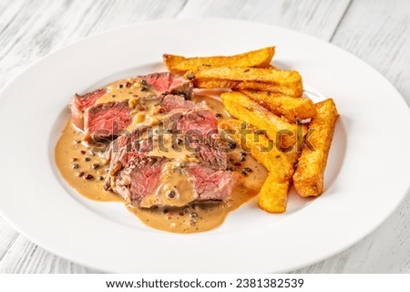 Steak au poivre - french steak with peppercorn sauce with french fries Royalty-Free Stock Photo #2381382539