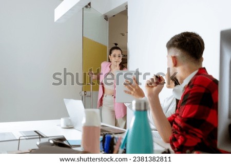 Young woman with glasses at the office door looks doubtfully at what two workers are pointing out to her. Boss and employees concept. Copyspace.