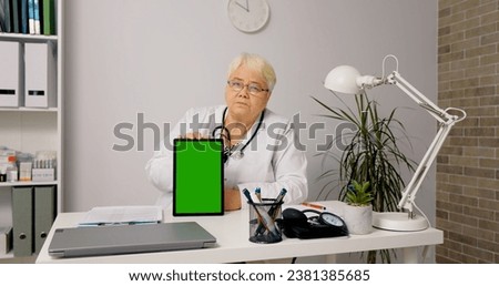 Portrait of female doctor telemedicine concept use green screen vertical tablet to see the patient and give advice. Technology in healthcare.