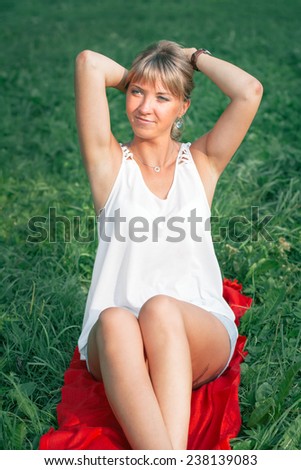 Portrait of beautiful young woman sits on green grass on natural background 