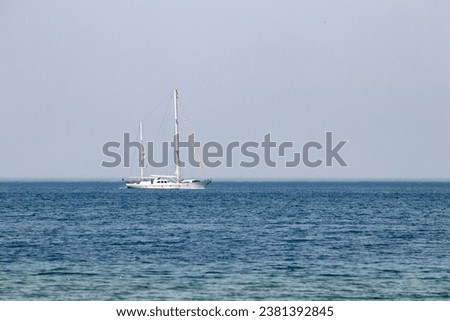 White sailboat sailing offshore in the blue sea. Minimalist photo idea concept. Marine transportation. Yachting. Metaphorical meaning of aloneness, loneliness. Selective focus. Noisy, grainy. Nobody.