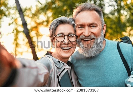 Wonderful sincere cheerful couple of gray haired mature smiling people taking selfie portrait on phone. Today's active retirees are enjoying life. A man with a gray beard and a woman in glasses. Royalty-Free Stock Photo #2381393109