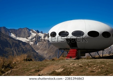 "Flying saucer" structure with an open door and a lowered ladder in the mountains                                Royalty-Free Stock Photo #2381396863