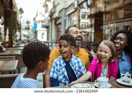 Stepfamily sharing joyful moments at an outdoor cafe in the city Royalty-Free Stock Photo #2381402409