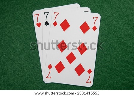 Three sevens. Winning hand in blackjack, pontoon. Lucky three of a kind on a green baize card table Royalty-Free Stock Photo #2381415555