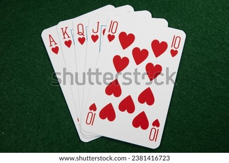 Royal Flush in hearts for the ultimate winning hand at poker on a green baize card table