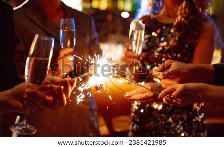 Glowing sparkles in hands. Group of happy people enjoying party with fireworks. Winter holiday.