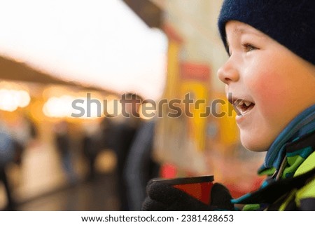 Close-up of kid boy in a gloves drinking tea outdoors and watching city lights. Drinking hot chocolate or tea after ice skating.