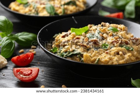 Creamy spaghetti squash pasta with parmesan cheese and sun dried tomato sauce served with pine nuts and basil. Royalty-Free Stock Photo #2381434161