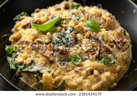 Creamy spaghetti squash pasta with parmesan cheese and sun dried tomato sauce served with pine nuts and basil. Royalty-Free Stock Photo #2381434179