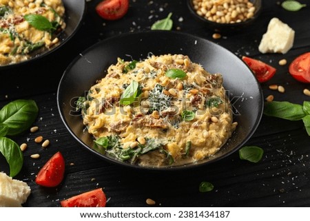 Creamy spaghetti squash pasta with parmesan cheese and sun dried tomato sauce served with pine nuts and basil. Royalty-Free Stock Photo #2381434187