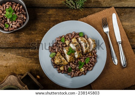 Roasted chicken breast with herbs and stewed beans, bio garlic roasted with wine and olive oil on top, fresh herbs, old school picture