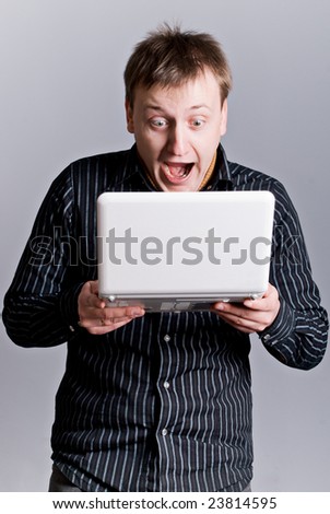 a young man looks in the monitor of notebook and surprised