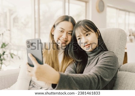 Happy Asian young adult women having fun taking selfie at home
