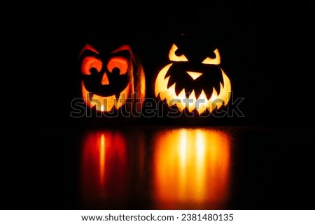 Halloween pumpkins with faces glowing in the dark on the floor. Reflections of the light. Halloween decorations, scary faces pumpkins.