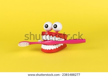 Wind-up toy mouth and nose with a toothbrush on a yellow background. The concept of oral care. Royalty-Free Stock Photo #2381488277