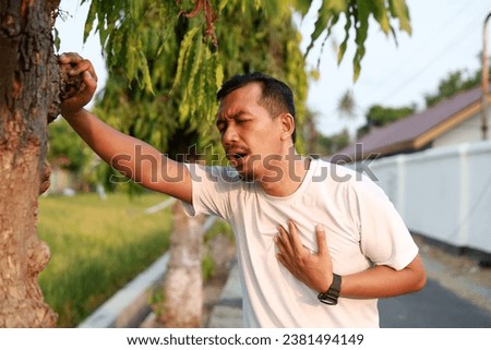 Asian Man runner athlete suffering from painful chest during outdoor running Royalty-Free Stock Photo #2381494149