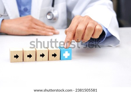 Finger of doctor touching the blue wooden block cube with healthcare medical icon symbol. Medical and health concept.