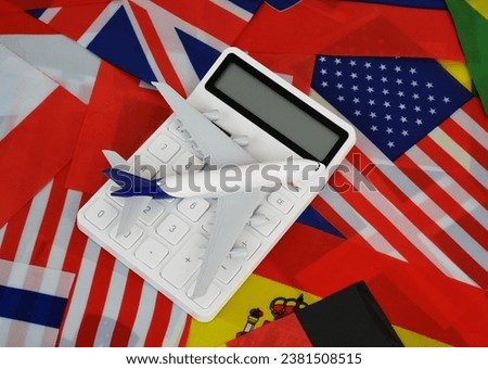 Airplane and calculator on many national flags background. Airplane tickets price, tourism and travel concept.