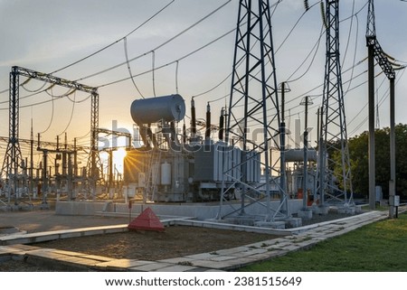 Insulators and transformers at an electrical substation. electrical equipment at sunset in the rays of the setting sun. Royalty-Free Stock Photo #2381515649