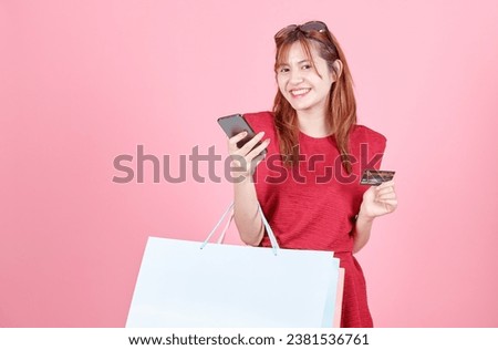 beautiful happy emotional positive cute woman posing. Portrait of excited beautiful girl wearing red dress and sunglasses telephone  credit card and holding shopping bags isolated over pink background