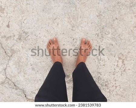 picture of feet on a bare cement floor and wearing black pants