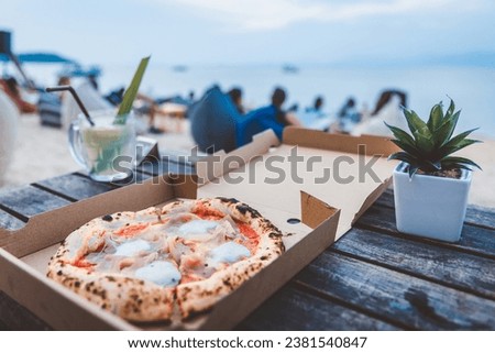 Fresh homemade Italian Pizza Margherita with parma ham and mozzarella cheese in paper box to go at beach club party in evening, Koh Samui, Thailand, Food delivery concept Royalty-Free Stock Photo #2381540847