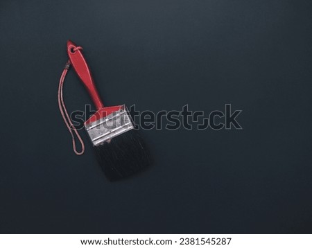 Paint brush, red handle, on a black background