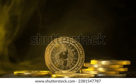 Uniswap gold coin in a golden haze. Physical Uni coin on a black background.