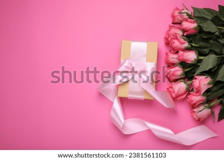Gift box and beautiful flowers on pink background, flat lay. Space for text