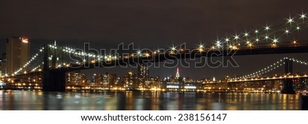Brooklyn Bridge over East River at night in New York City Manhattan with lights and reflections.