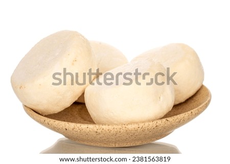 Several frozen semi-finished cheesecakes on a ceramic saucer, macro, isolated on white background.