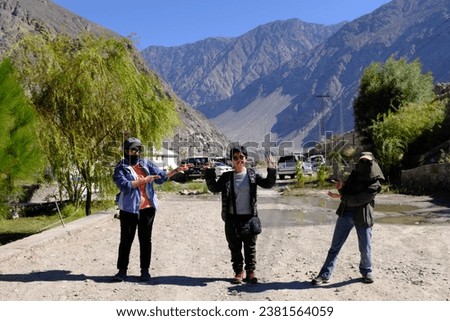 A group of Asian female tourists with fully covered outfit to avoid dust taking a mockery picture before taking a jeep ride at Chilas Pass, Karakoram Highway, Pakistan.