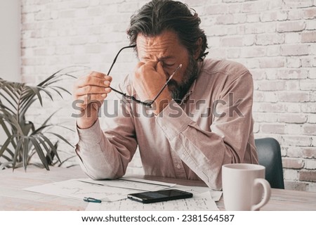 Man at the desk receiving bad news on the phone and touching his front with desperation. Business problems people in the office. One mature professional freelance with migraine and tired stressed Royalty-Free Stock Photo #2381564587